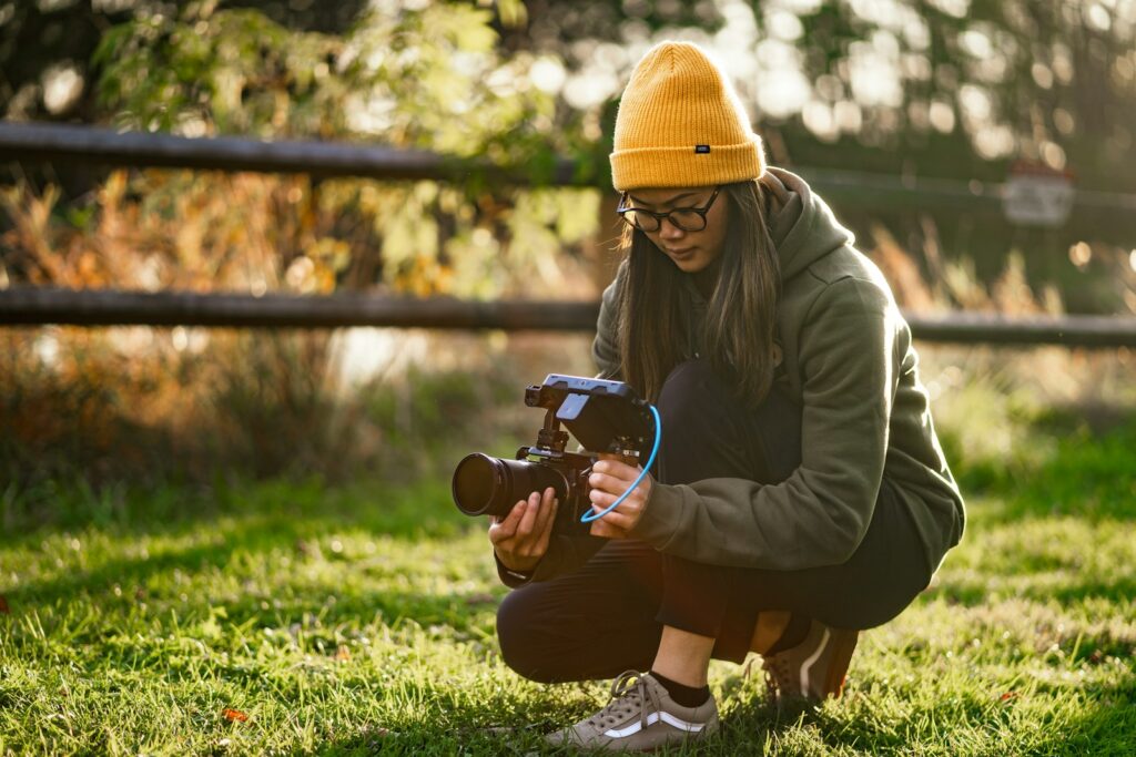 a woman kneeling down while holding a camera in a video production set.